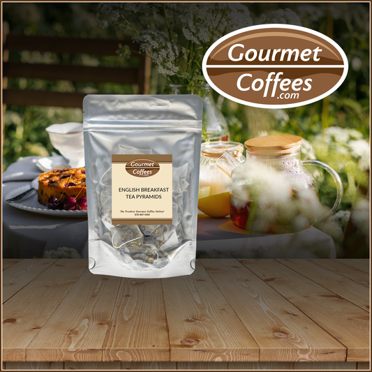 Packaged English Breakfast tea pyramids with a blurred background of a tea set and cake.